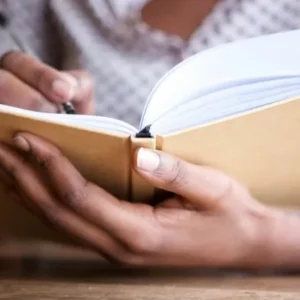 Hand holding open journal on table