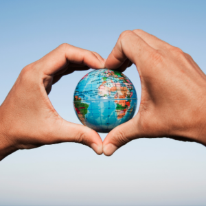 A person shaping their hands into a heart shape with an image of the world in the middle